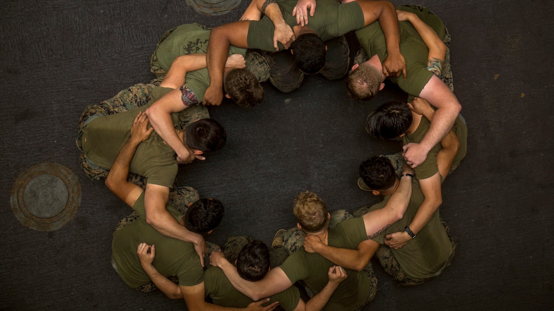 As seen from above, a group of Marines stand in a circle.