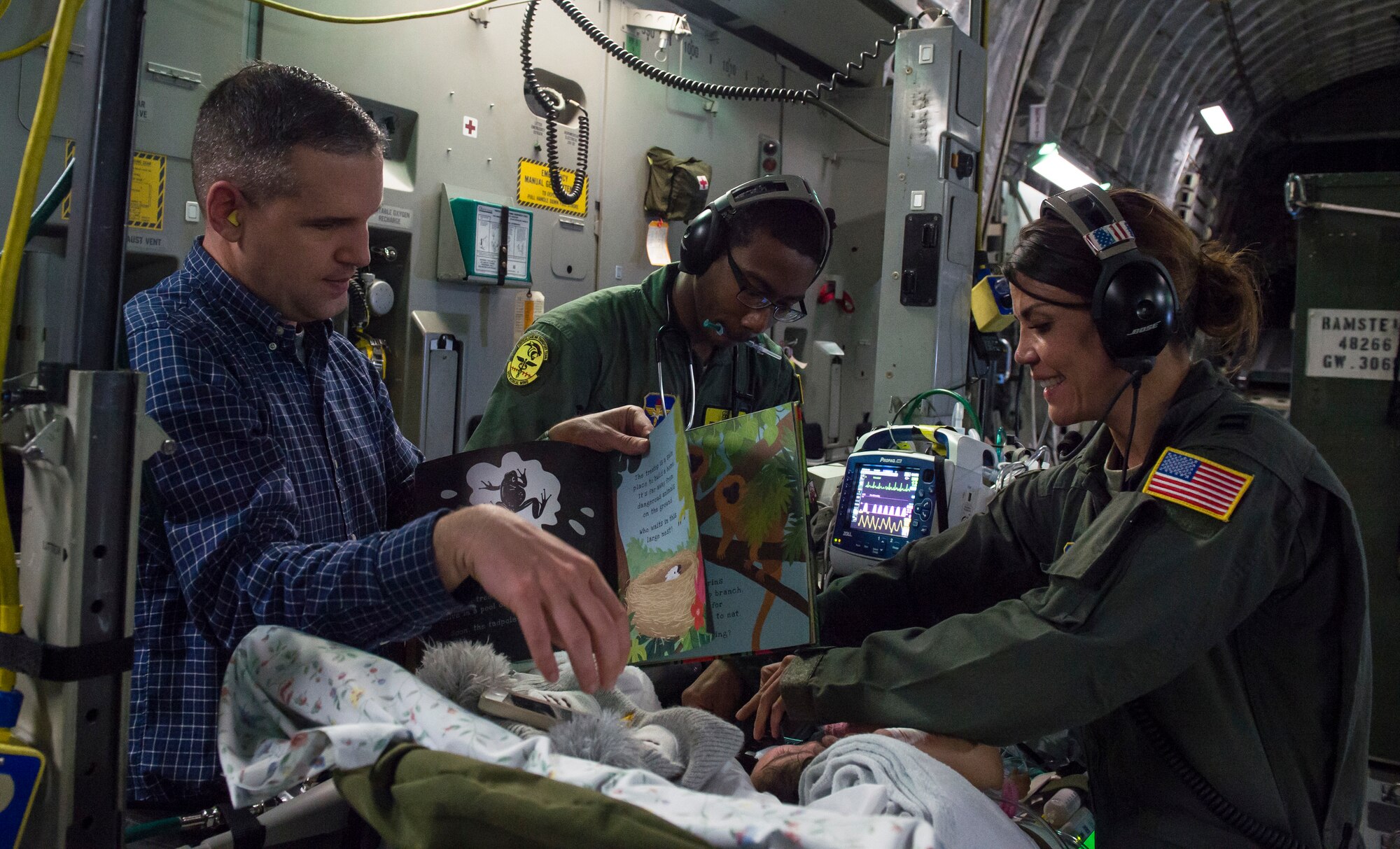 59th Medical Wing Critical Care Air Transport Team members, along with the patient's father, entertain an infant during an air transport mission from Germany to Walter Reed National Medical Center, Bethesda, Md., April 19th, 2018. CCATT teams maintain the standard of care provided to critically ill, injured or burned patients who require continuous stabilization and advanced care during transport to the next level of care. (U.S. Air Force photo by Senior Airman Keifer Bowes)