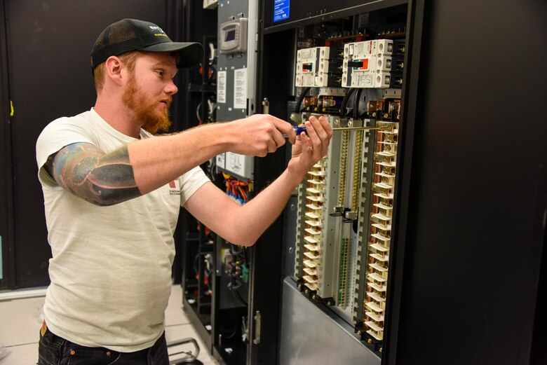 Ridge Yadori, a Lockheed Martin field technician, installs circuit breakers into one of two new F-35 simulator power distribution units