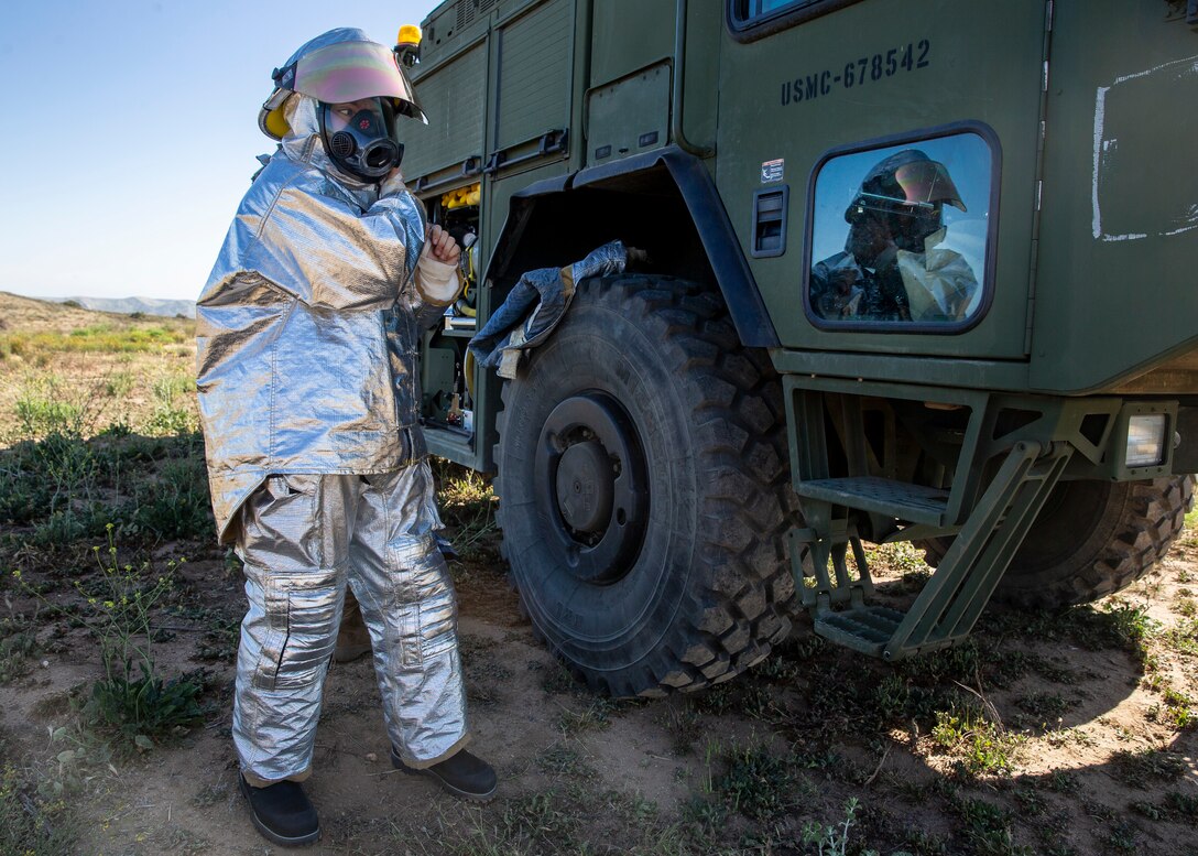 Lance Cpl. Austin Jones, an expeditionary firefighting and rescue Marine with Marine Wing Support Squadron (MWSS) 372, Marine Aircraft Group 39, 3rd Marine Aircraft Wing, dons his personal protective gear near a P19-R at Marine Corps Base Camp Pendleton, Calif., April 26. MWSS-372 and Marine Light Attack Helicopter Squadron (HMLA) 469 conducted a day and night forward arming and refueling point for training in aerial operations support. (U.S. Marine Corps photo by Lance Cpl. Clare J. McIntire/Released)