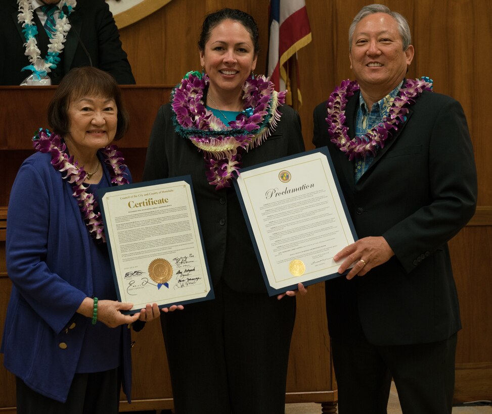 (Center) Dr. Lisa Charles, Pacific Air Forces Sexual Assault Prevention and Response Program Manager, receives a certificate and proclamation from (left) Ann Kobayashi, Honolulu City Council member, and (right) Roy Amemiya, Honolulu city managing director, at Honolulu City Hall April 18, 2018.