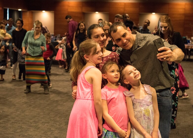 Army Master Sgt. Warren Mitchell, 59th Signal Battalion, takes a picture with his daughters Ruthie, age 11, Honna, age 6, Charlie, age 5, Almaira, age 9, during the Father/Daughter and Mother/Son Dance at Joint Base Elmendorf-Richardson’s Arctic Warrior Events Center, April 27, 2018. The event was sponsored by the Family Advocacy Program, the Sexual Assault Prevention and Response Office, the 673d Medical Group, and the USO. Attendees had the chance to partake in Information booths, a build-your-own ice cream sundae bar and dancing.