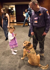 Kyla, age 3, daughter of Tech. Sgt. Emily Williams, from the 673d Medical Support Squadron, greets Pagan, a service dog trained to provide comfort during the Father/Daughter and Mother/Son Dance at Joint Base Elmendorf-Richardson’s Arctic Warrior Events Center, April 27, 2018. The event was sponsored by the Family Advocacy Program, the Sexual Assault Prevention and Response Office, the 673d Medical Group, and the USO. Attendees had the chance to partake in Information booths, a build-your-own ice cream sundae bar and dancing.