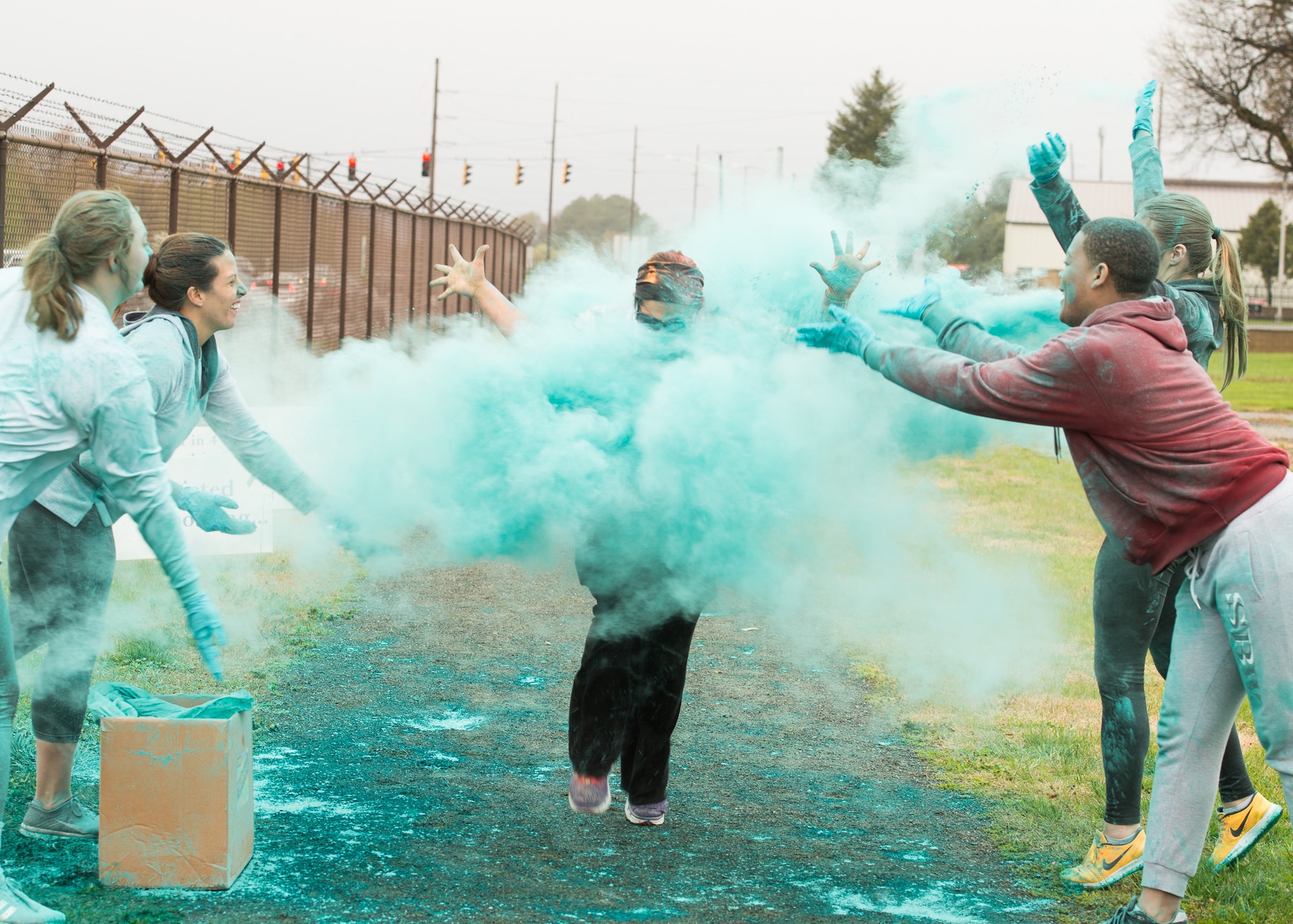 Course volunteers throw teal-colored powder on 5k runners during the Sexual Assault Awareness Month Color Run April 25, 2018, at Dover Air Force Base, Del. Volunteers waited at five stations along the course to throw brightly colored powder at passing runners with each color having a special meaning to remind Airmen of the resources available to members of the community. Blue for Mental Health and Family Advocacy; Green for Green Dot; Teal for 24/7 SAPR Victim Advocacy; Red for Chaplain Corps; Yellow for Leadership; Orange for Special Victim Counsel. (U.S. Air Force photo by Mauricio Campino)