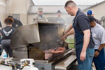 Master Sgts. Elden Pelletier (front), and Matthew Lucas, 436th Medical Group and 436th Maintenance Group first sergeants respectively, grill hot dogs for Team Dover members April 27, 2018, at the chapel on Dover Air Force Base, Del. At the conclusion of the Wingman Day Amazing Race, participants and Team Dover members  socialized while eating free food. (U.S. Air Force photo by Roland Balik)