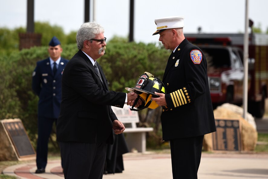 President of the Military Firefighter Heritage Foundation, Mike Robertson, presents Chief Mark Guiliano, Fire Emergency Services Flight, 96 Civil Engineer Squadron, Eglin Air Force Base, Florida, with a firefighter helmet in honor of Assistant Chief Edward Vanner at the Fallen Department of Defense Firefighter Memorial ceremony on Goodfellow Air Force Base, Texas, April 27, 2018. Vanner was a member of the Rhode Island Air National Guard 143rd Airlift Wing before passing away June 17, 2017. (U.S. Air Force photo by Airman 1st Class Seraiah Hines/Released)