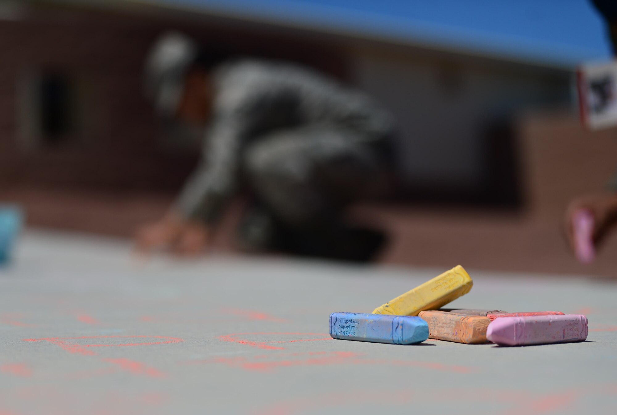 Airman 1st Class Celine, 432nd Operations Support Squadron aviation resource manager, writes on the sidewalk during a Chalk the Walk event April 20, 2018, at Creech Air Force Base, Nev. By early afternoon the walks leading to the base dining facility were flooded with supportive words and drawings in a variety of vibrant hues. (U.S. Air Force photo by Airman 1st Class Haley Stevens)