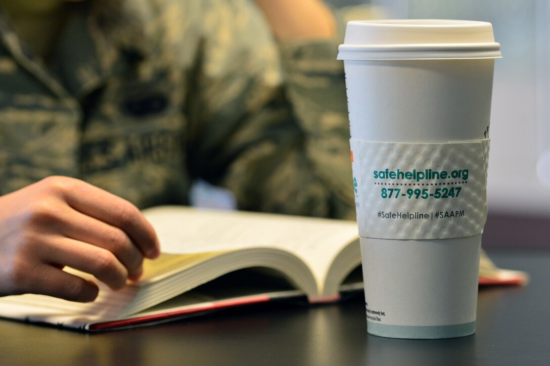 An Airman with the 432nd Wing/432nd Air Expeditionary Wing reads a book in the base coffee shop April 12, 2018, at Creech Air Force Base, Nev. Jennifer, a 432nd WG/432nd AEW sexual assault prevention and response victim’s advocate, paired with the coffee shop on base to distribute cup sleeves that display the sexual assault helpline website for April, Sexual Assault Awareness and Prevention Month. (U.S. Air Force photo by Airman 1st Class Haley Stevens)