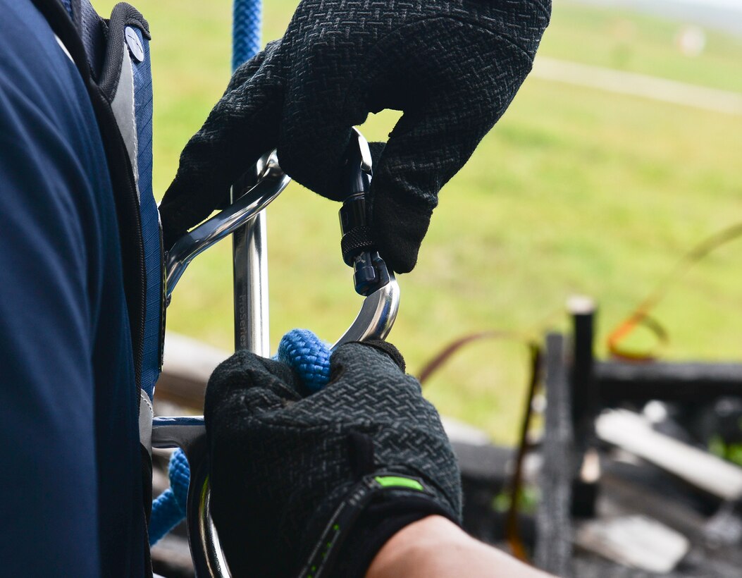 One fireman unfastens the hook holding the harness of another after rapelling April 22, 2018, at Andersen Air Force Base, Guam. The rapell training took place during Silver Flag, a routine civil engineering exercise that included participants from the U.S., Australia,The Republic of Singapore, and the Republic of Korea. (U.S. Air Force photo by Tech. Sgt. Jake M. Barreiro)