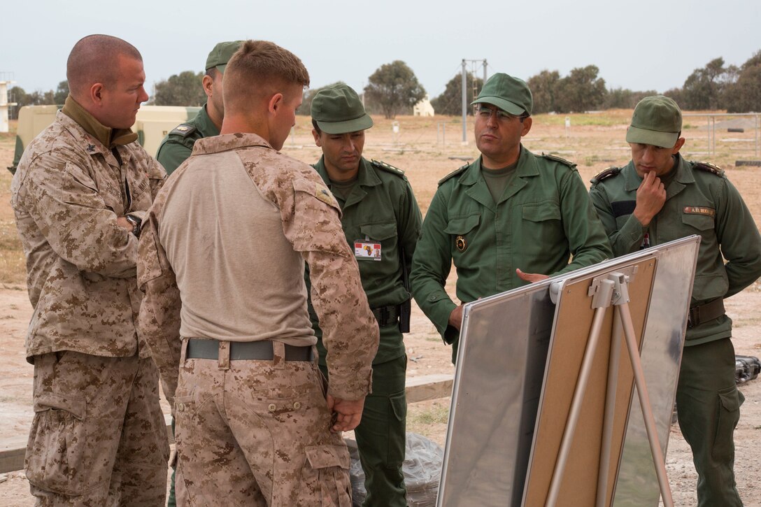 U.S. service members and members of the Moroccan Armed Forces gather around a diagram of close-quarter combat tactics during Exercise African Lion 2018, in Tifnit, Morocco, April 20, 2018. African Lion is an annual, multinational, joint-force exercise improving interoperability between participating nations. (U.S. Marine Corps photo by Lance Cpl. Tessa D. Watts)