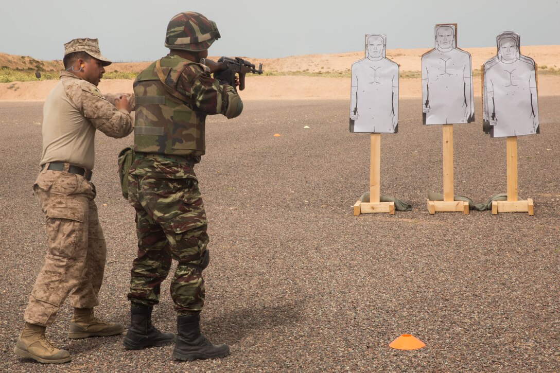 U.S. Marine Lance Cpl. Bryan Verduzco, infantry team leader with Fleet Antiterrorism Security Team, guides a member of Gendarmerie through speed reload training during Exercise African Lion 2018, in Tifnit, Morocco April 20, 2018. African Lion is an annual, multinational, joint-force exercise improving interoperability between participating nations. (U.S. Marine Corps photo by Lance Cpl Tessa D. Watts)