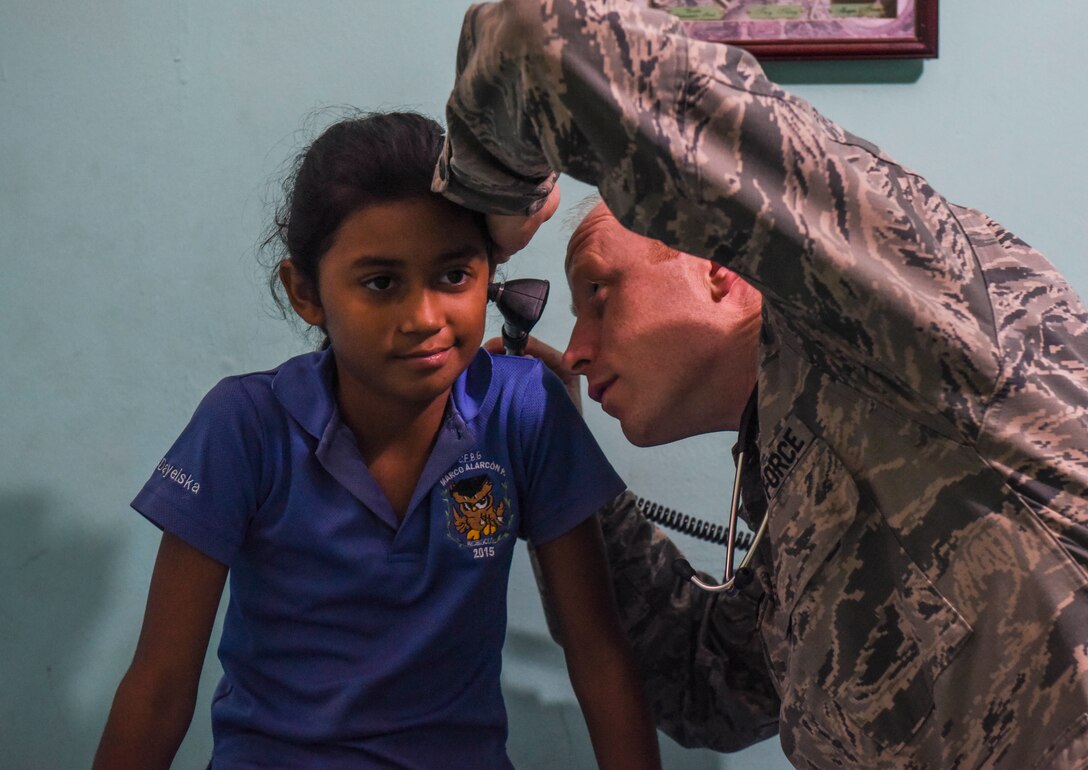 U.S. Air Force Maj. Adam Hebdon, 346th Expeditionary Medical Operations Squadron family physician, checks the ears of a local girl in Meteti, Panama, April 10, 2018. Hebdon was part of an Embedded Health Engagement Team, which gave him a unique learning experience by submerging him into local clinics. The team was participating in Exercise New Horizons 2018, which will assist communities throughout Panama by providing medical assistance and building facilities such as schools, a youth community center and a women’s health ward. (U.S. Air Force photo by Senior Airman Dustin Mullen)