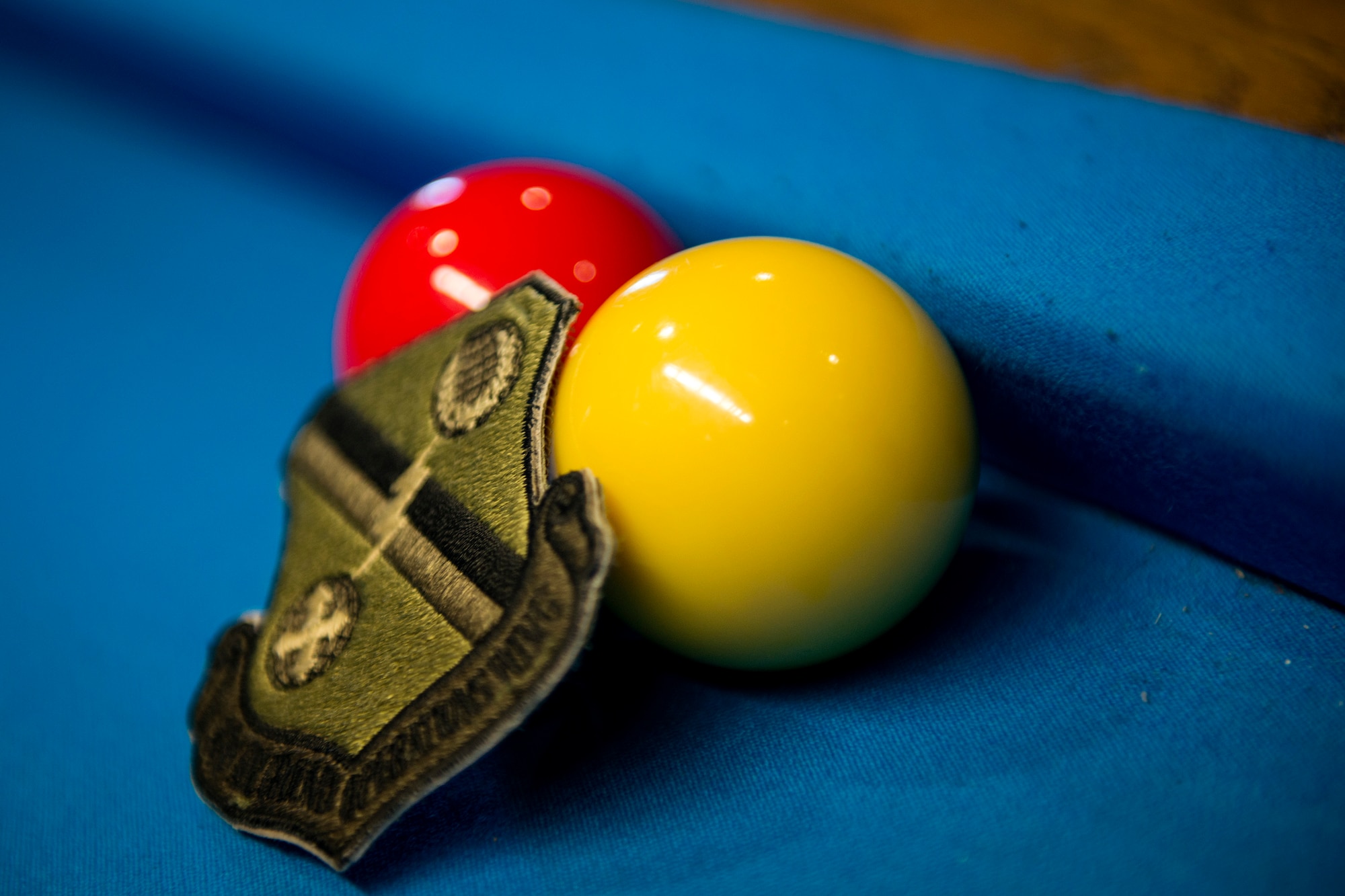 Billiard balls and a uniform patch rest on a billiard table during a spouses crud tourney, April 27, 2018, at Moody Air Force Base, Ga. The Moody spouses built the event around teamwork and comradery, giving them an opportunity to experience a long-held tradition amongst the Air Force fighter and rescue squadrons. Though the game originated in the Royal Canadian Air Force, it has since been adopted by the U.S. (U.S. Air Force photo by Airman 1st Class Erick Requadt)