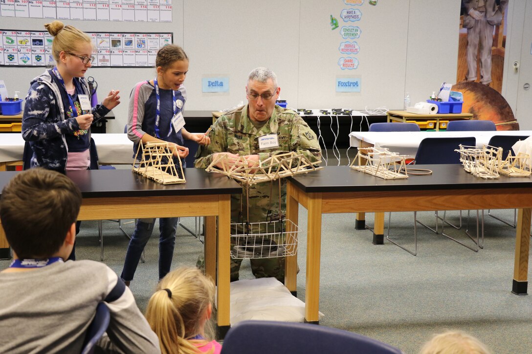 Col. Stephen Bales, U.S. Army Corps of Engineers' Middle East District commander, tests teams' bridges for amount of weight each could hold before failing. This team's bridge failed at 18 pounds.