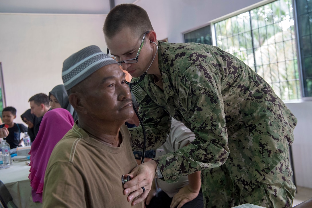 A Navy physician listens to a patient’s breathing during a checkup.