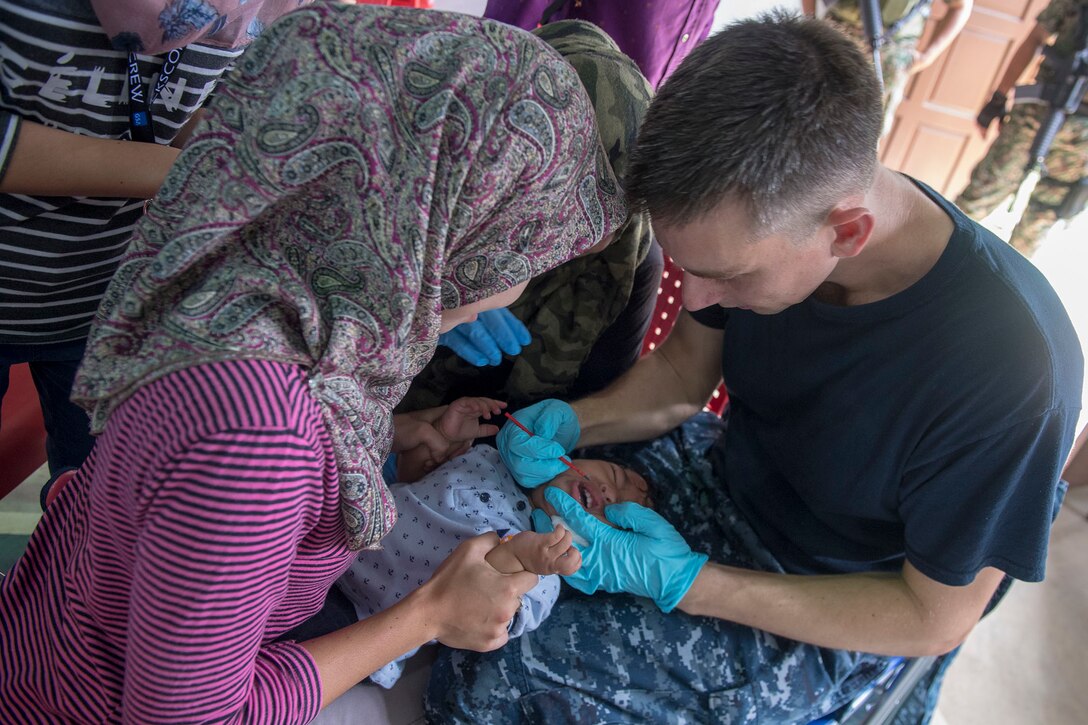 A Navy doctor examines a patient.