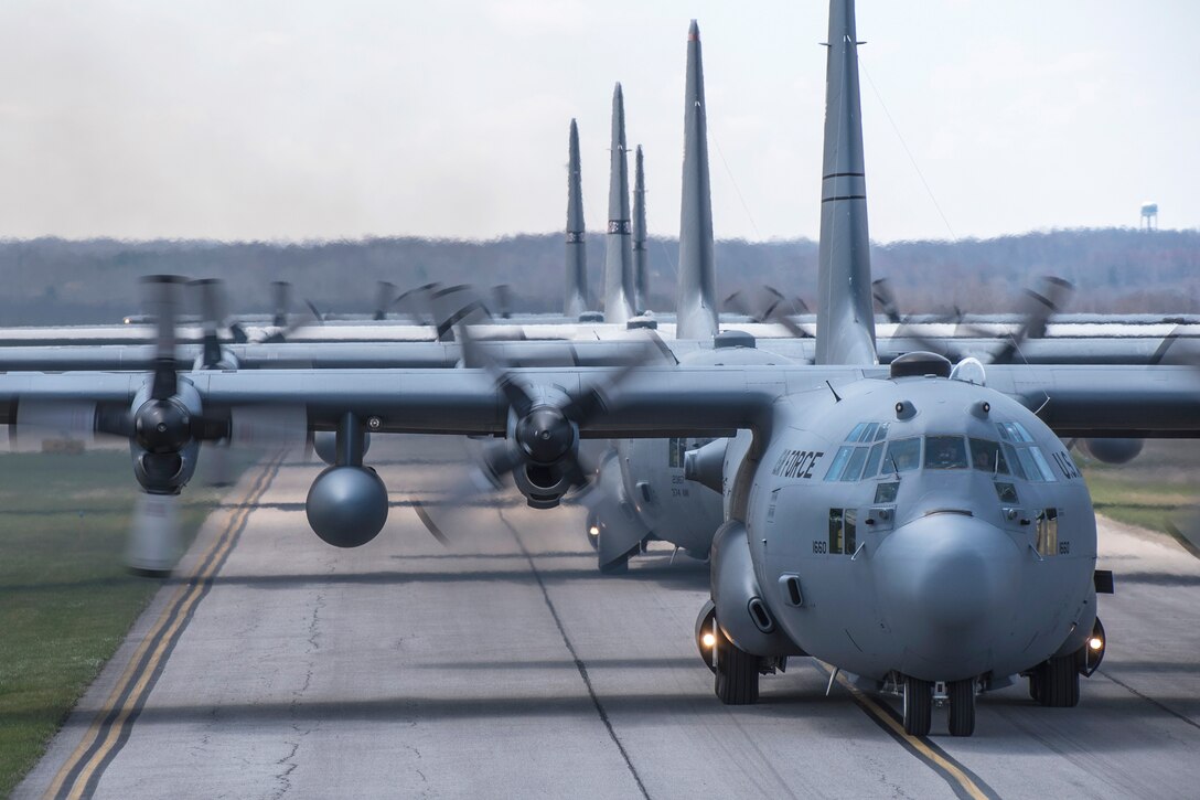 Air Force pilots and crew chiefs taxi five C-130H Hercules aircraft.