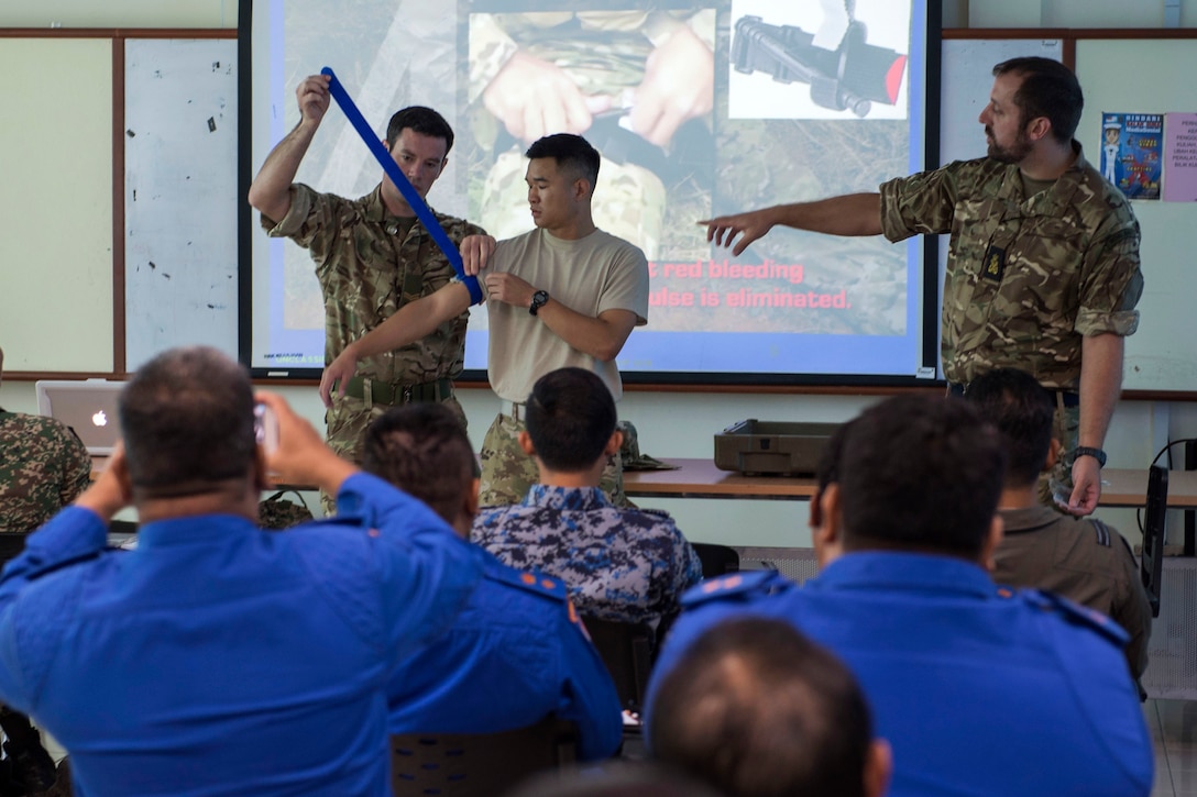 Troops demonstrate the proper way to apply a tourniquet during a basic first responder course.