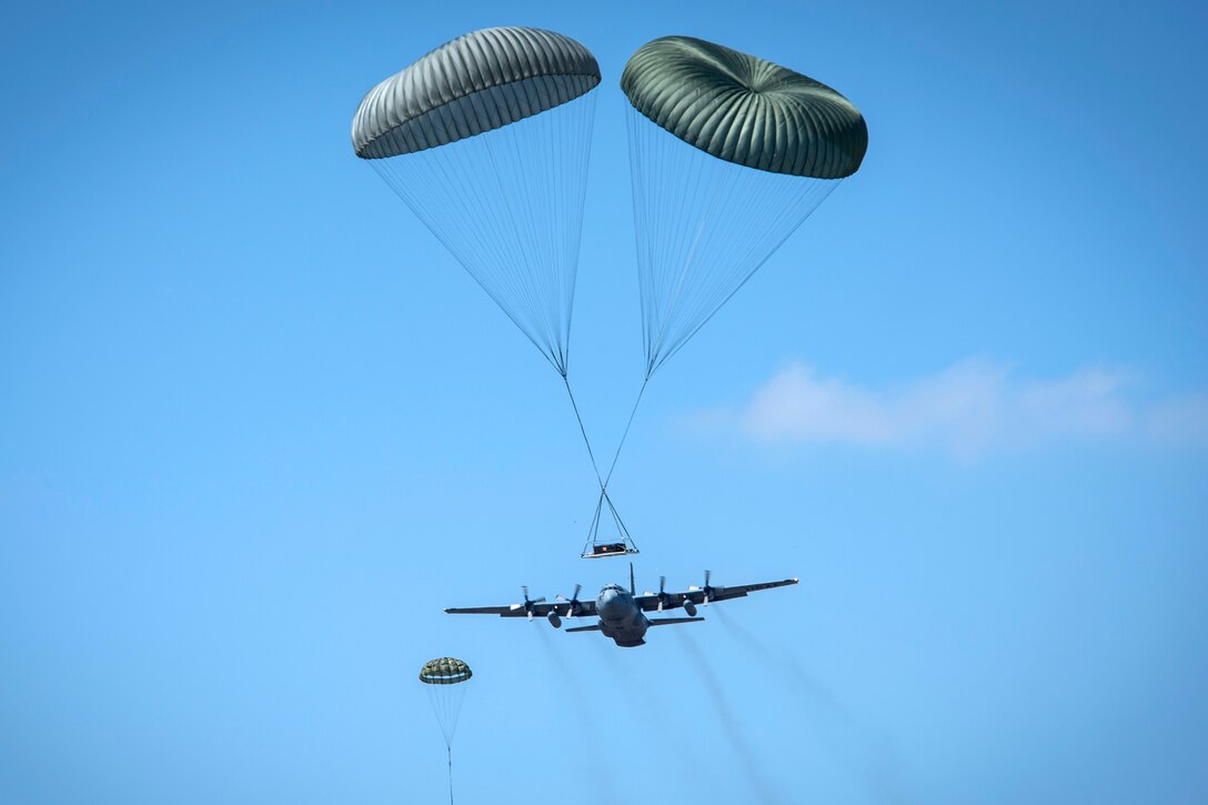 Five C-130H Hercules aircraft conduct a coordinated airdrop exercise.