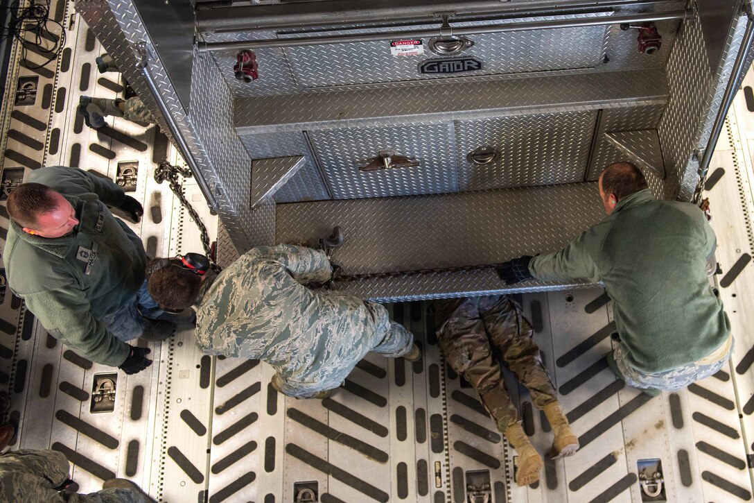 Airmen secure a vehicle inside a C-17 Globemaster III.