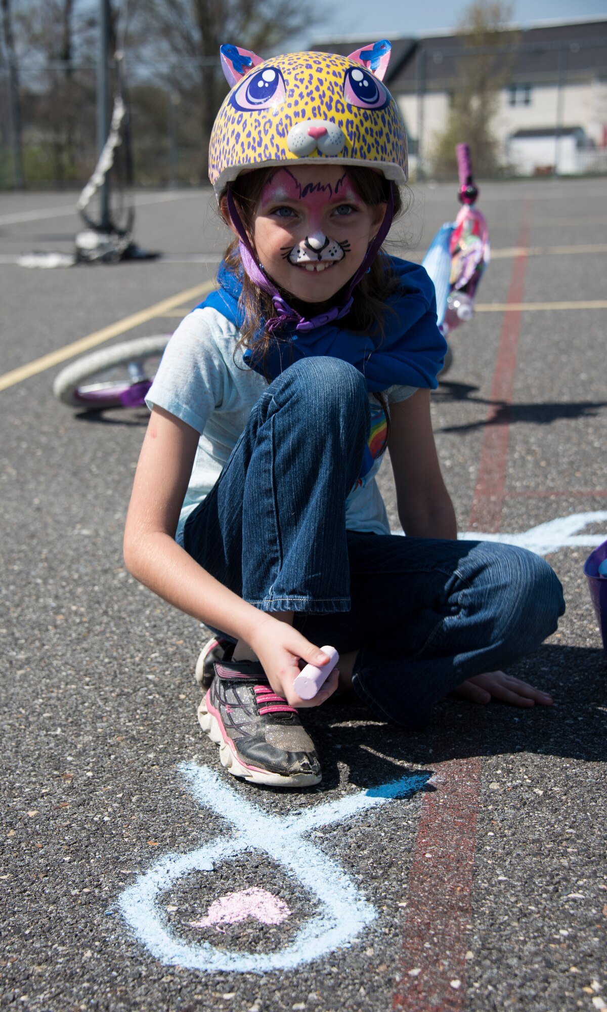 Hannah, a military child, draws the symbol for child abuse prevention on a basketball court during the Kids on Wheels Parade on Joint Base McGuire-Dix-Lakehurst, N.J., April 28, 2018. Hannah said her favorite color is teal, the official color for Sexual Assault Awareness and Prevention Month. (U.S. Air Force photo by Airman Ariel Owings)