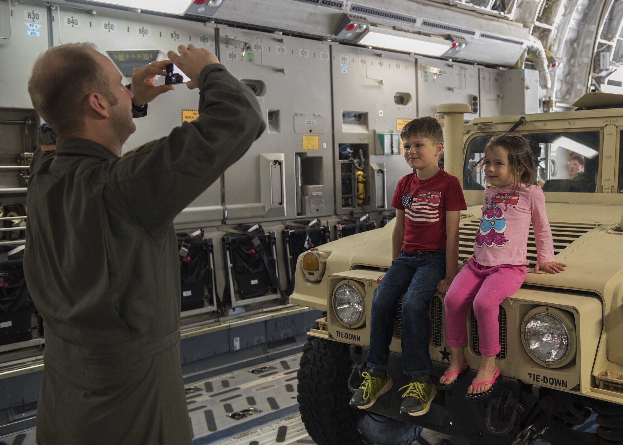 U.S. Air Force Maj. Christopher Schlener, chief of command post assigned to the 58th Airlift Squadron takes a photo of his children sitting on a Humvee inside a C-17 Globemaster III, April 26, 2018, at Altus Air Force Base, Okla.