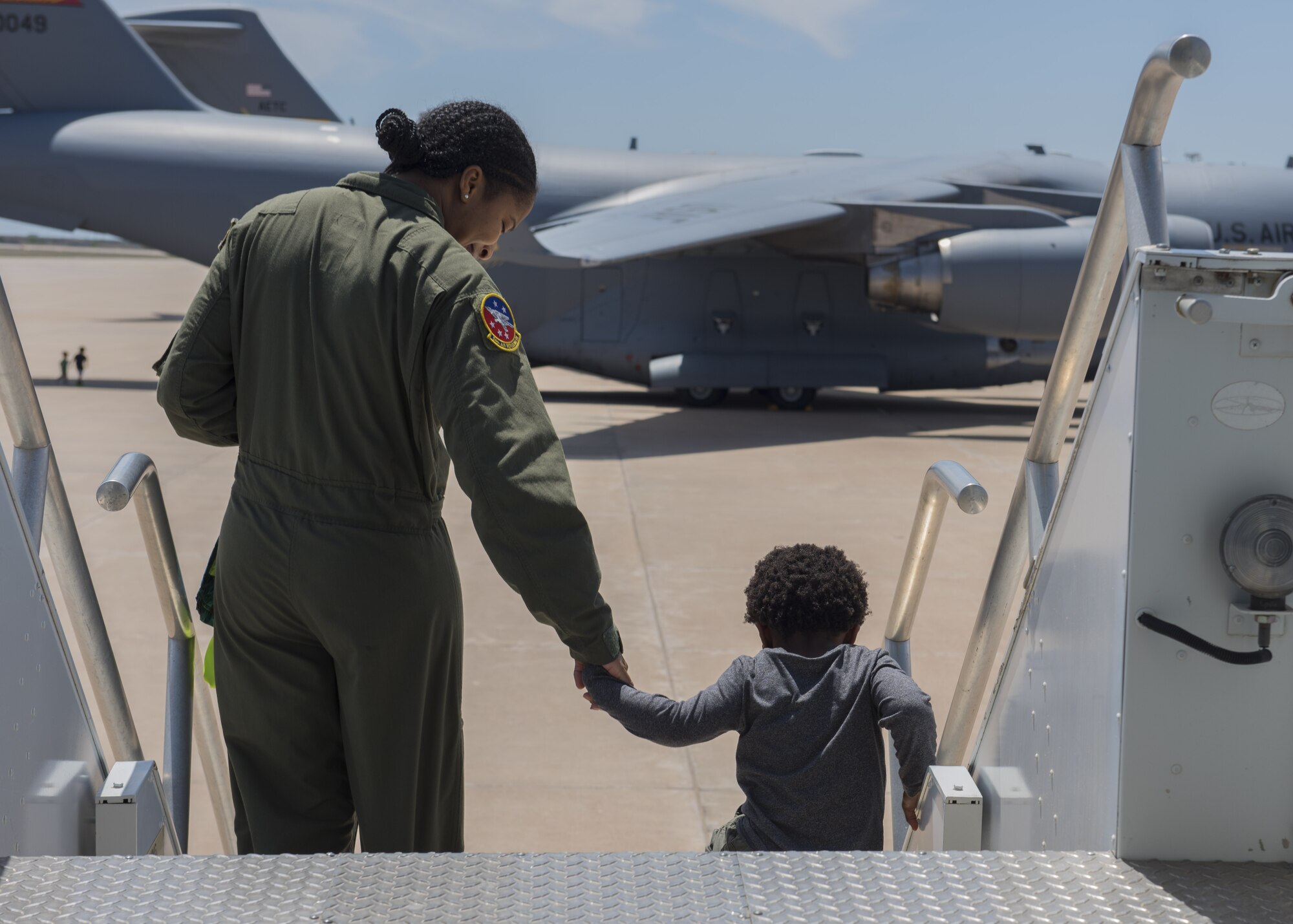 U.S. Air Force Staff Sgt. Liahna Childs, an instructor boom assigned to the 54th Air Refueling Squadron, and her son exit a KC-135 Stratotanker, April 26, 2018, at Altus Air Force Base, Okla.