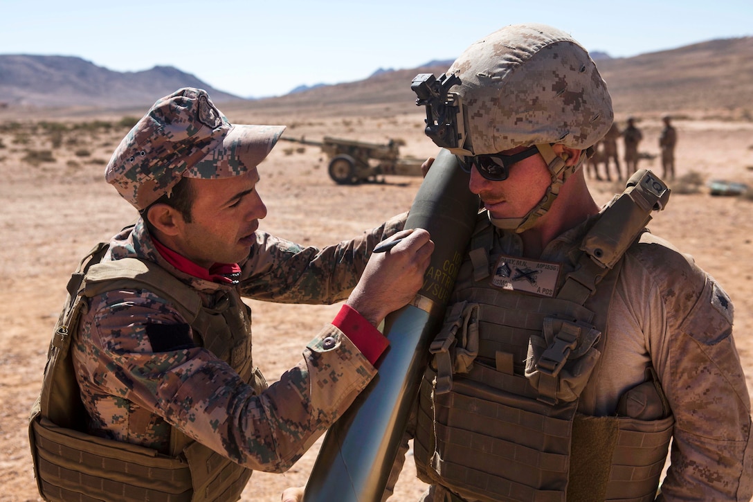 A Jordanian marine writes the name of U.S. Marine Corps Sgt. Micah N. Pauly on a 105 mm Howitzer round.