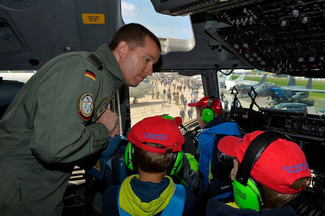 German air force Maj. Rico Persy, a foreign exchange pilot stationed at Joint Base Charleston, S.C., shows German school children the features of a U.S. Air Force C-17 Globemaster III in Berlin, Germany, April 27, 2018. The Military Personnel Exchange program allows U.S. and foreign pilots to train train closely with their allies and familiarize themselves with other aircraft. (U.S. Air Force photo by Senior Airman Joshua Magbanua)