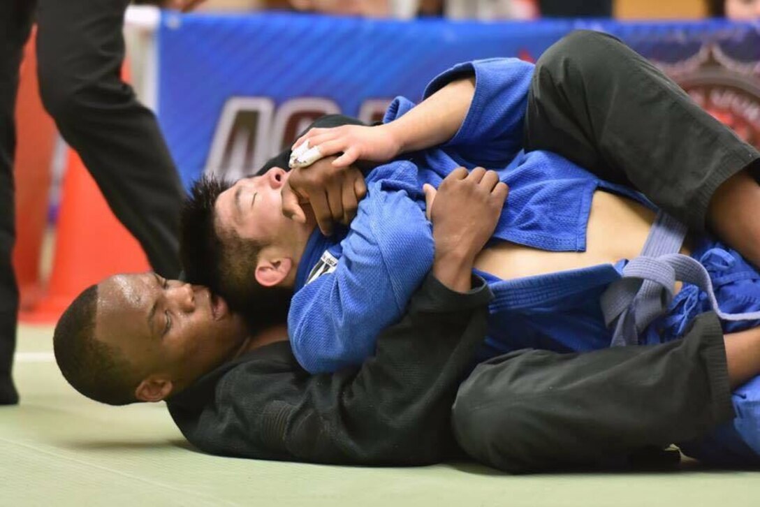 A competitor puts a choke hold on another during a jiujitsu match.