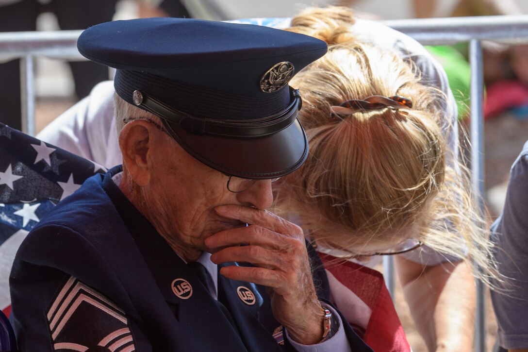 A veteran and civilian bow their heads during a ceremony.