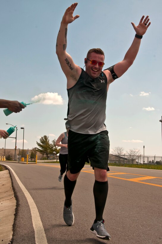 A service member is sprayed with teal powder while running in the race.