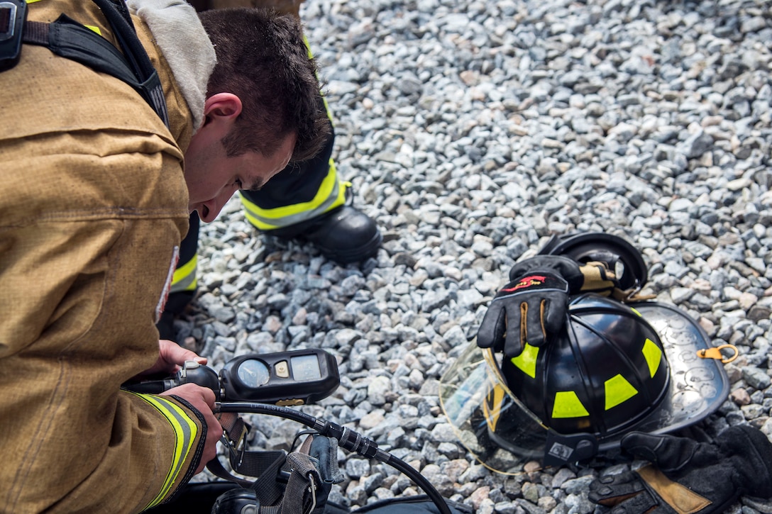 An airman firefighter checks the levels on his oxygen tank before a training exercise.