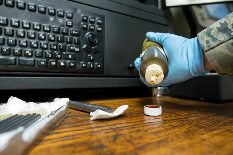 Senior Airman Louisa Doyle, 23d Maintenance Squadron non-destructive inspection (NDI) specialist, pours aircraft engine oil, May 2, 2018, at Moody Air Force Base, Ga. NDI technicians use various methods to complete these inspections such as X-ray, florescent dye penetrant, oil analysis and ultrasonic scanning to examine and inspect numerous aircraft parts and components to ensure that they are in usable condition. (U.S. Air Force photo by Airman 1st Class Eugene Oliver)