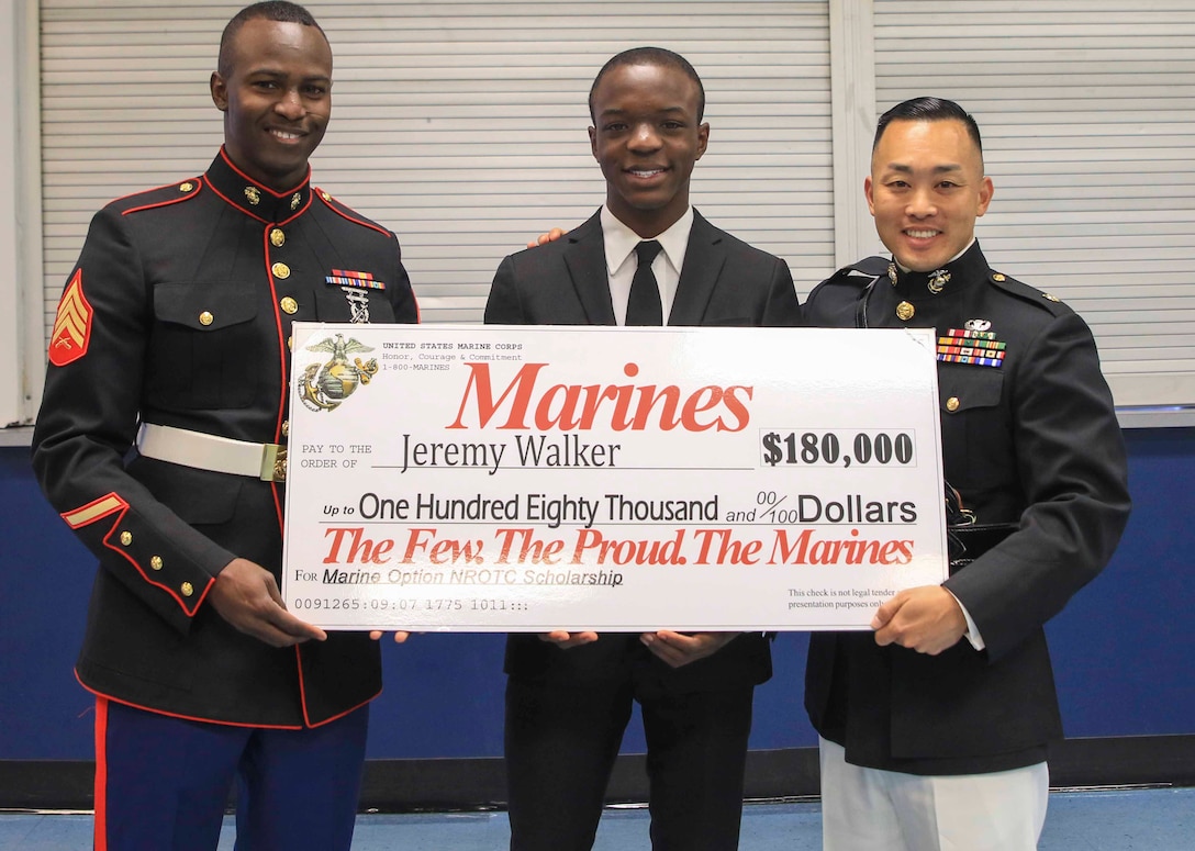 Major Richard Lee (right), commanding officer, Recruiting Station Tampa and Sgt. Jeremy Woody (left), canvassing recruiter, Recruiting Substation Temple Terrace, present Jeremy Walker, a senior at King High School, Tampa, Fl., the Naval Reserve Officer Training Corps Marine Option Scholarship during an awards ceremony April 12, 2018. Walker will be granted the opportunity to serve his country as a Marine Corps officer upon completion of his degree. (Official Marine Corps photo by Sgt. Calvin Shamoon/ Released)
