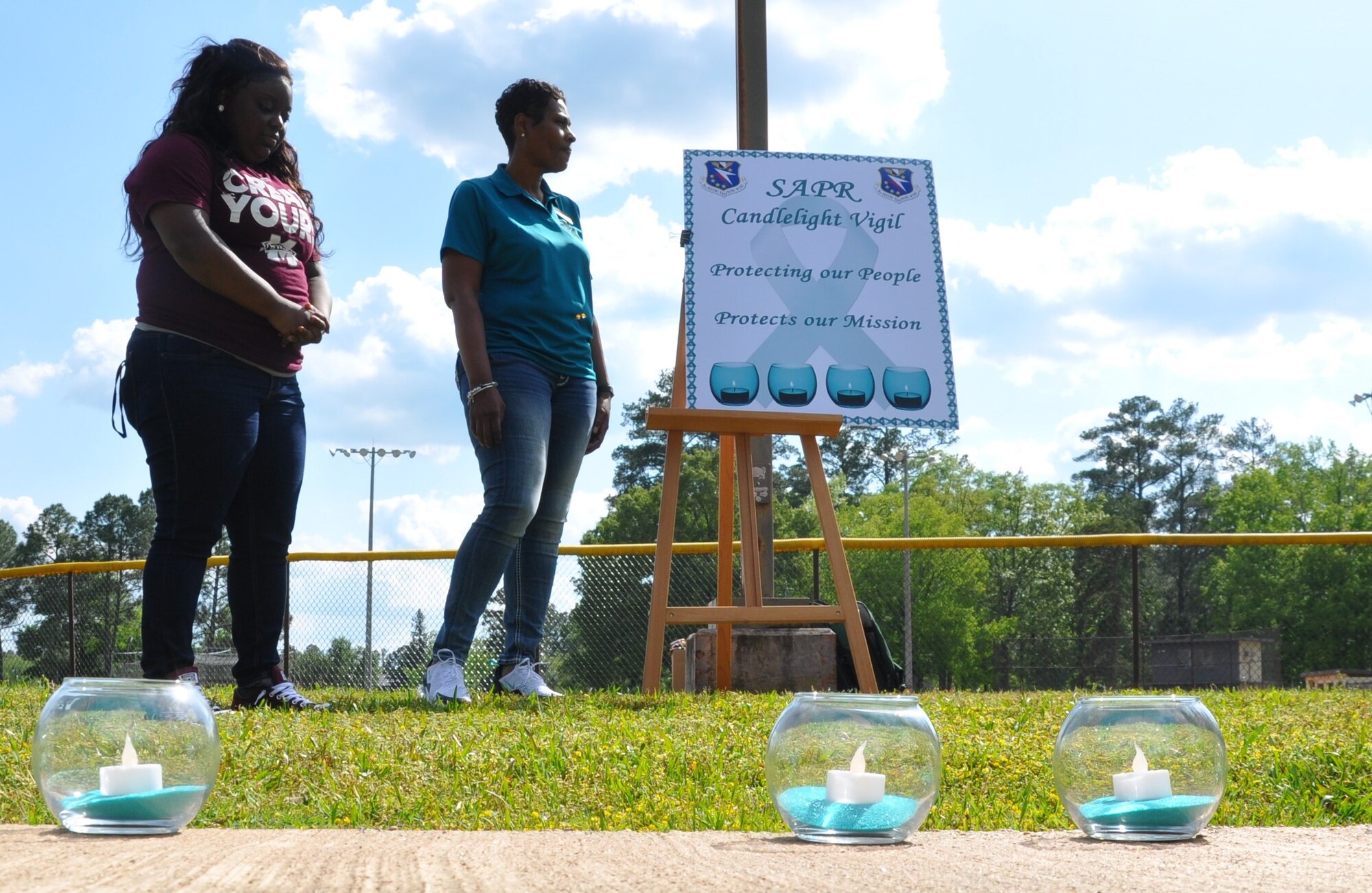 Dr. Marcia Stewart, 14th Flying Training Wing Sexual Assault Prevention and Response program manager, and a volunteer from Mississippi State University hold a moment of silence for the victims of sexual assault April 27, 2018, on Columbus Air Force Base, Mississippi. The SAPR team worked with MSU and other colleges to help educate and raise awareness about sexual assault prevention and what to do if someone has be affected. (U.S. Air Force photo by Sonic Johnson)