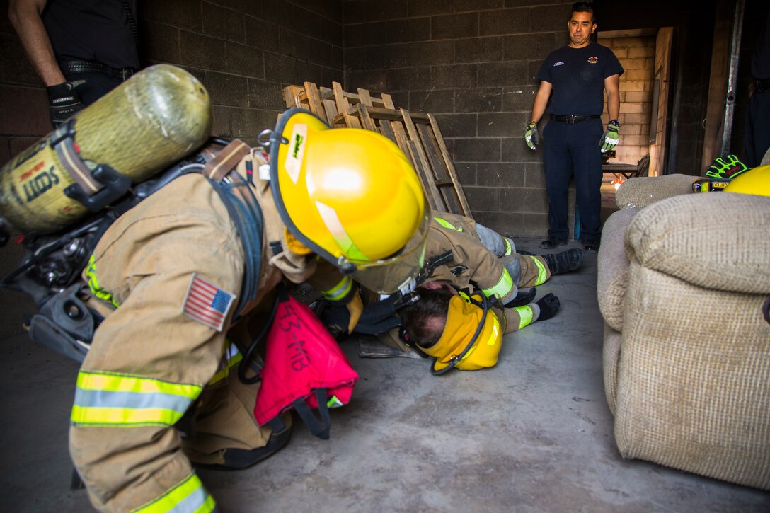 Two newly hired firefighters with Marine Corps Air Station (MCAS) Yuma’s fire department conduct “New Hire Training” at the stations fire department training building aboard MCAS Yuma, Ariz., Tuesday, April 17, 2018. The training teaches new firefighters all the basic skills they need to be successful at their job. This includes: how to climb the ladder, basic EMS training, how to employ and use the fire hose, and rescue drags used for removing civilians from dangerous environments. (U.S. Marine Corps photo by Cpl. Isaac D. Martinez)