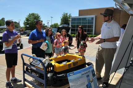 Naval Surface Warfare Center Panama City Division engineer Bill Porter explains the Dive Buddy project to 2018 Invention Convention attendees April 28, 2018 at Florida State University Panama City campus. The 2018 Invention Convention featured a science fair for middle school to college students and technical capabilities, such as SEAL Delivery Vehicles, underwater unmanned vehicles, unmanned aviation systems and Navy diving technologies, presently being fielded at NSWC PCD. The goal of the event was to make science accessible to everyone, regardless of cost. (Released) U.S. Navy photo by Jacqui Barker, NSWC PCD.