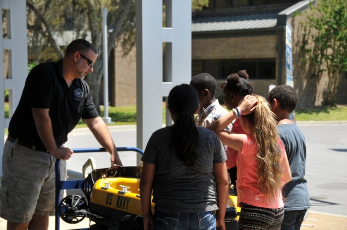 Naval Surface Warfare Center Panama City Division Dive Buddy Project Lead Lee Cofer explains the Dive Buddy project to 2018 Invention Convention attendes April 28, 2018 at Florida State University Panama City campus. The 2018 Invention Convention featured a science fair for middle school to college students and technical capabilities, such as SEAL Delivery Vehicles, underwater unmanned vehicles, unmanned aviation systems and Navy diving technologies, presently being fielded at NSWC PCD. The goal of the event was to make science accessible to everyone, regardless of cost. (Released) U.S. Navy photo by Jacqui Barker, NSWC PCD.