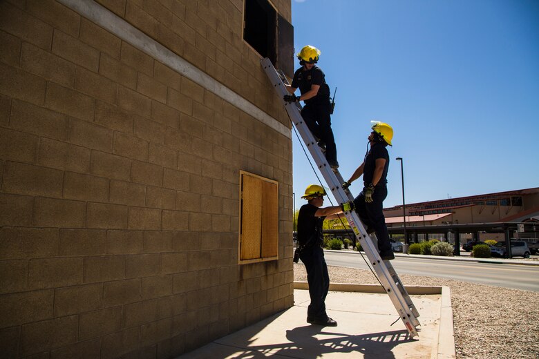 Two newly hired firefighters with Marine Corps Air Station (MCAS) Yuma’s fire department conduct “New Hire Training” at the stations fire department training building aboard MCAS Yuma, Ariz., Tuesday, April 17, 2018. The training teaches new firefighters all the basic skills they need to be successful at their job. This includes: how to climb the ladder, basic EMS training, how to employ and use the fire hose, and rescue drags used for removing civilians from dangerous environments. (U.S. Marine Corps photo by Cpl. Isaac D. Martinez)