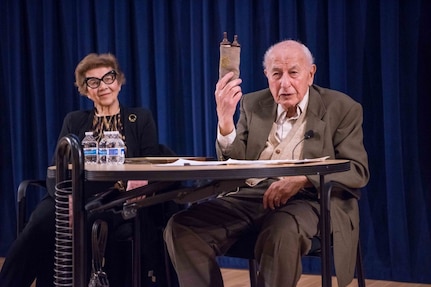 Fred Flatow shows the audience a Torah Scroll he found as a child in a burned-down synagogue. Flatow gave a detailed account of his memories as a Jewish boy growing up in East Prussia at the time of the Nazi regime during the Naval Surface Warfare Center, Carderock Division Holocaust Remembrance event in West Bethesda, Md., on April, 24, 2018. Flatow was joined by his wife, Ursel. (U.S. Navy photo by Jake Cirksena/Released)