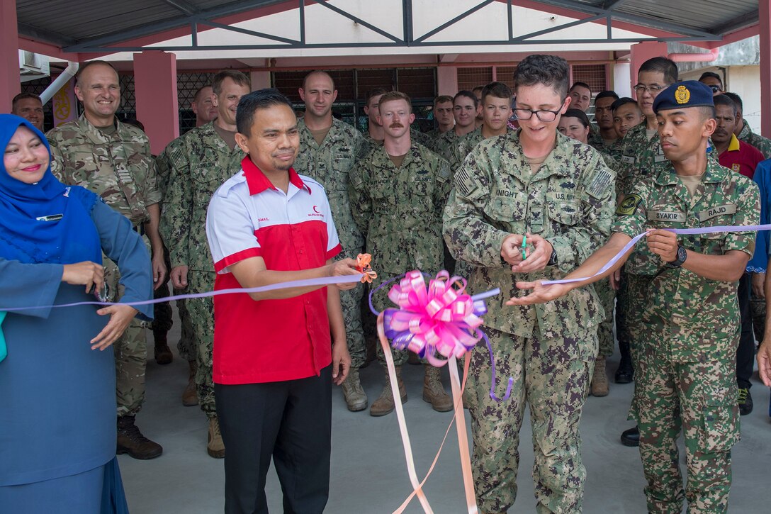 Navy Petty Officer 2nd Class Courtney Knight cuts the ribbon during an engineering project conclusion ceremony at Sek Keb TMN Taman Primary School in support of exercise Pacific Partnership 2018 in Tawau, Malaysia.