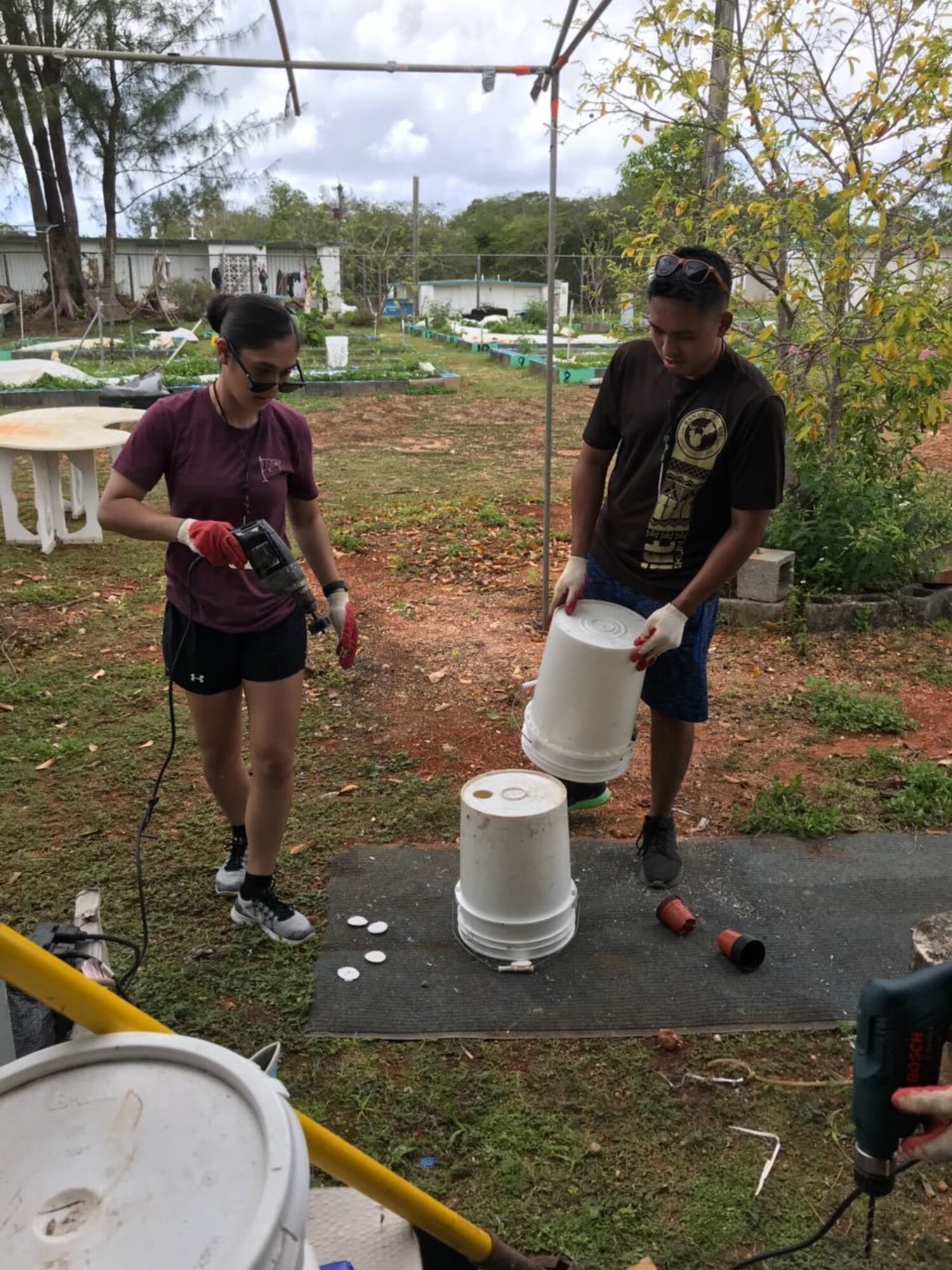Members of the Air Force Reserve’s 624th Regional Support Group’s Development and Training Flight, trainee Breanna Aguon and Majuni Obillo volunteer April 18, 2018, in Dededo, Guam, to drill drainage holes in buckets which will be used to plant vegetables for a non-profit organization Island Girl Power during their unit training assembly. The D&TF is a program designed to prepare new enlistees physically and mentally for basic training. (Courtesy photo