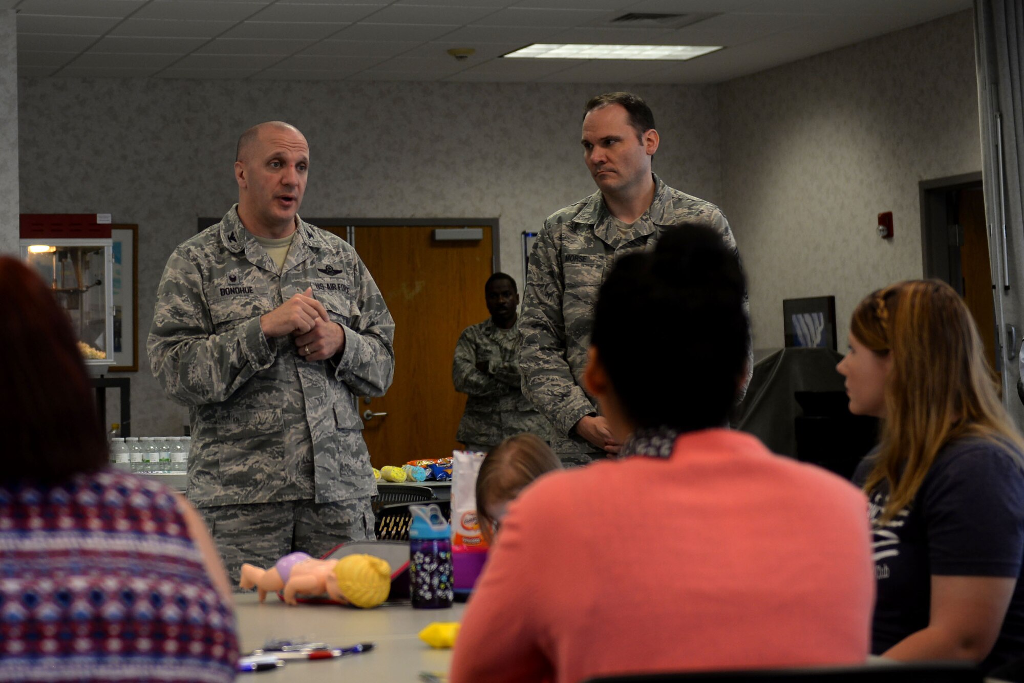 Two men wearing the Airman Battle Uniform speak to three women in different colored shirts.