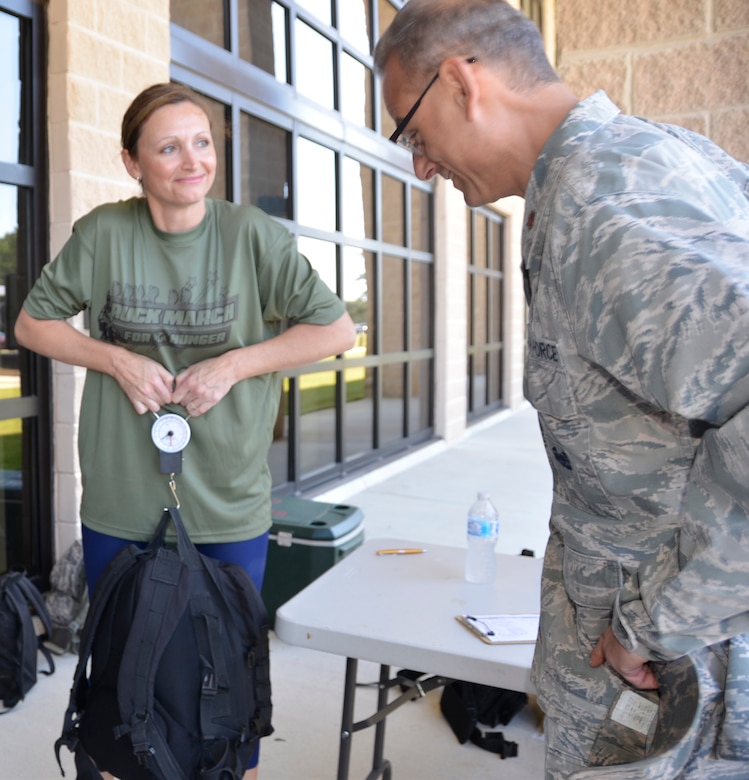 Senior Master Sgt. Tricia DeLuna, 1st Air Force (Air Forces Northern) Manpower & Personnel Directorate, weighs the backpack of  Maj. Peter Shinn, 601st air Operations Center executive officer, prior to the start of the second annual 5K Ruck March For Hunger May 4 here. Military and civilian members of 1st Air Force and the 601st Air Operations Center and their family members participated to raise awareness about hunger along with food donations for community food pantries and agencies in the Panama City area.  Nearly 100 people donned 30+ lb. ruck sacks, back packs or donated food to support the food drive which raised 1,911 lbs. The drive began last year when a 1st Air Force Airman saw a statistic stating that numerous students in Bay County were going to school hungry.
