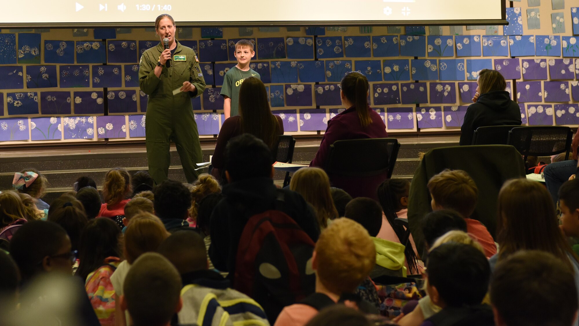 During Carter Lake Elementary School’s Month of the Military Child ceremony April 27, 2018 at Joint Base Lewis-McChord, Wash., Lt. Col. Beth Lane, 62nd Airlift Wing director of staff, left, encourages participation from kindergarten through fifth graders as her son, Josh Lane (8) rewarded enthusiastic responders with prizes.
