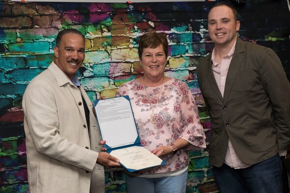 Col. David Cochran, left, 167th Airlift Wing vice commander, presented Jenny Regalia, a key volunteer for the 167th Airlift Squadron, with an award for her outstanding volunteer service. Her son, Tech. Sgt. Chris Regalia, right, is a loadmaster for the 167th AS. (U.S. Air National Guard photo by Senior Master Sgt. Emily Beightol-Deyerle)