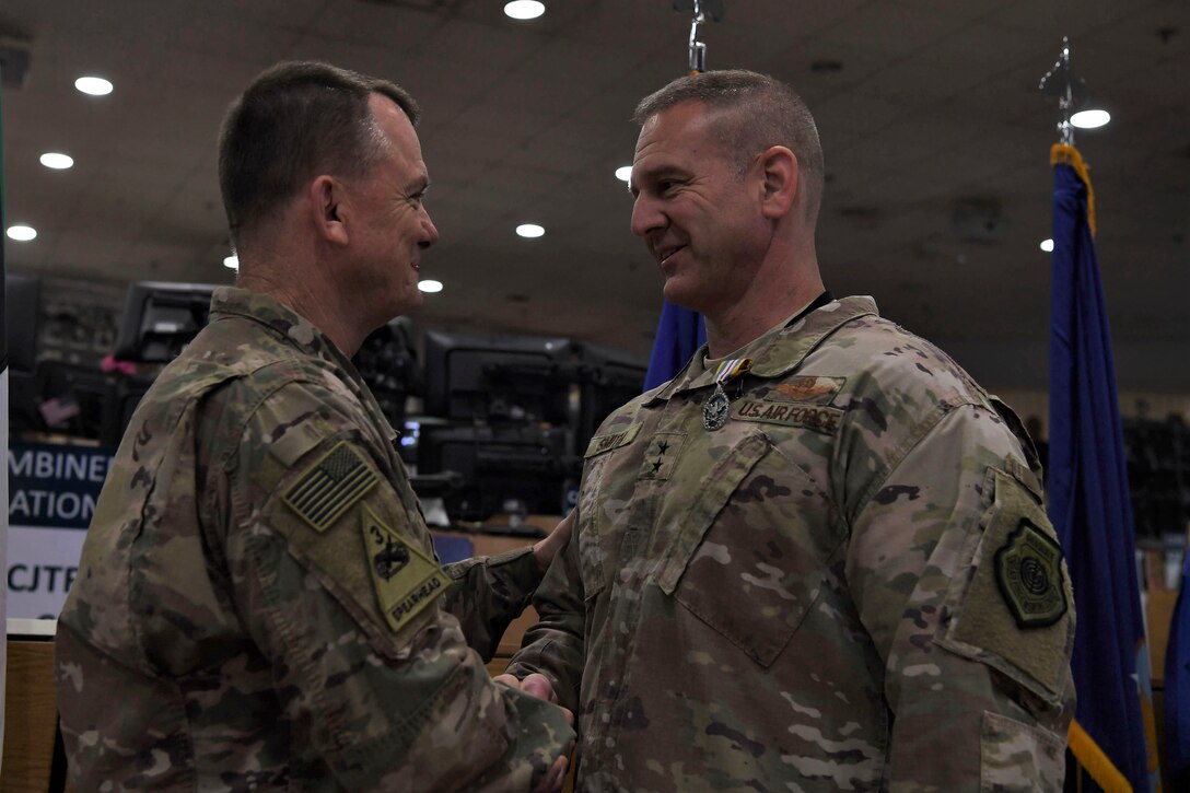 Maj. Gen. Dirk Smith (right), the outgoing 9th Air Expeditionary Task Force - Levant commander, shakes hands with U.S. Army Lt. Gen. Paul Funk, Combined Joint Task Force - Operation Inherent Resolve commander, after receiving the Defense Superior Service Medal during a change of command ceremony May 5, 2018, at an undisclosed location in Southwest Asia.