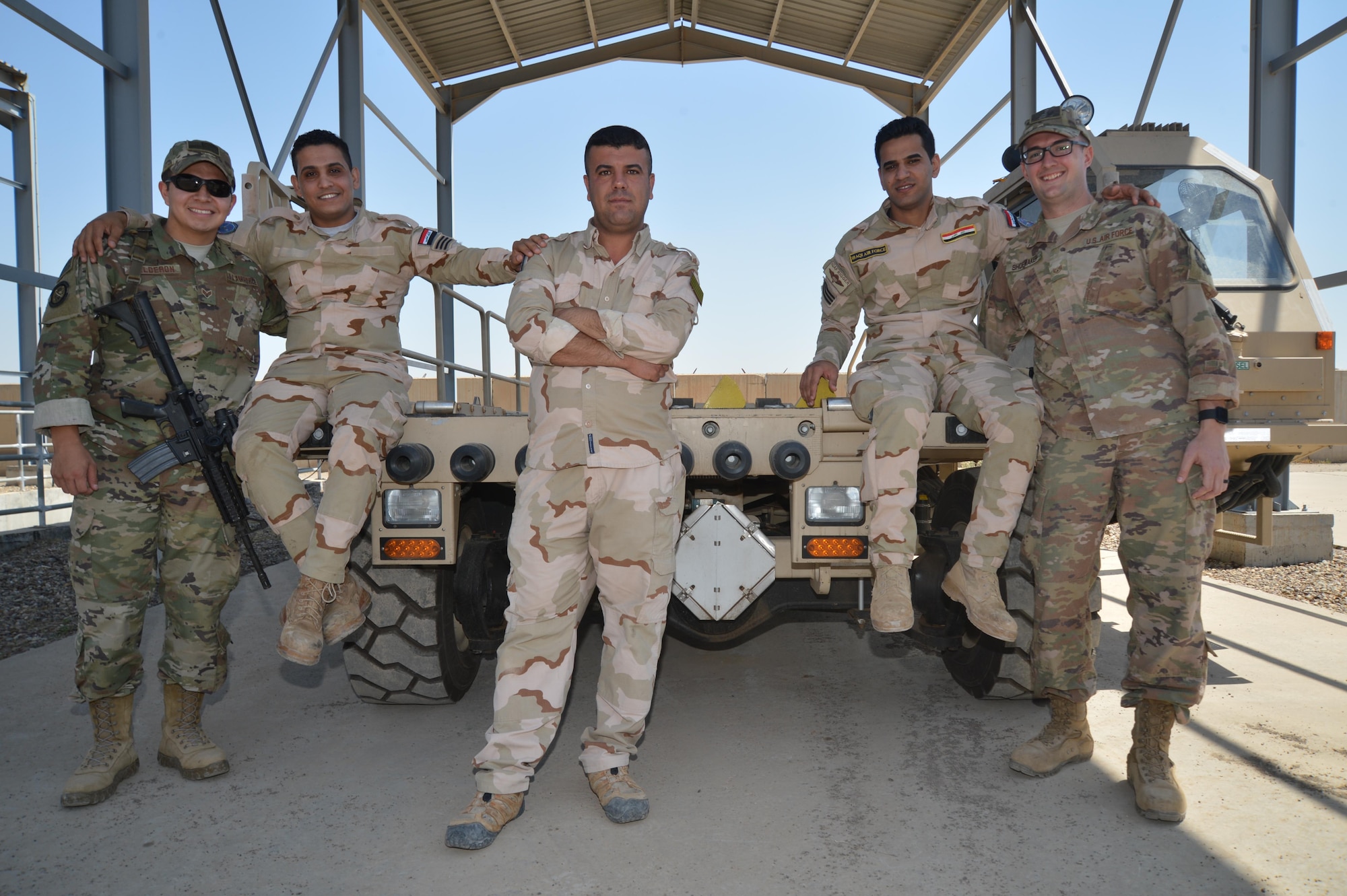 Senior Airman Juan Calderon (far left) and Staff Sgt. Michael Shoemaker (far right), 370th Air Expeditionary Advisory Group air advisors, pose for a photo with Iraqi Air Force airmen at Al Muthana Air Base, April 23, 2018. The air advisors work with their Iraqi counterparts to assist with training and safety protocols specific to their expertise. (Air Force photo by Staff Sgt. William Banton)