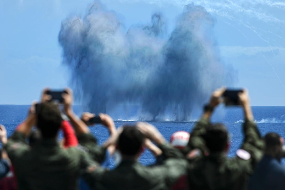 Sailors, Marines and guests watch an ordnance demonstration.